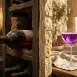Verre de vin rosé pétillant en cave avec bouteilles anciennes